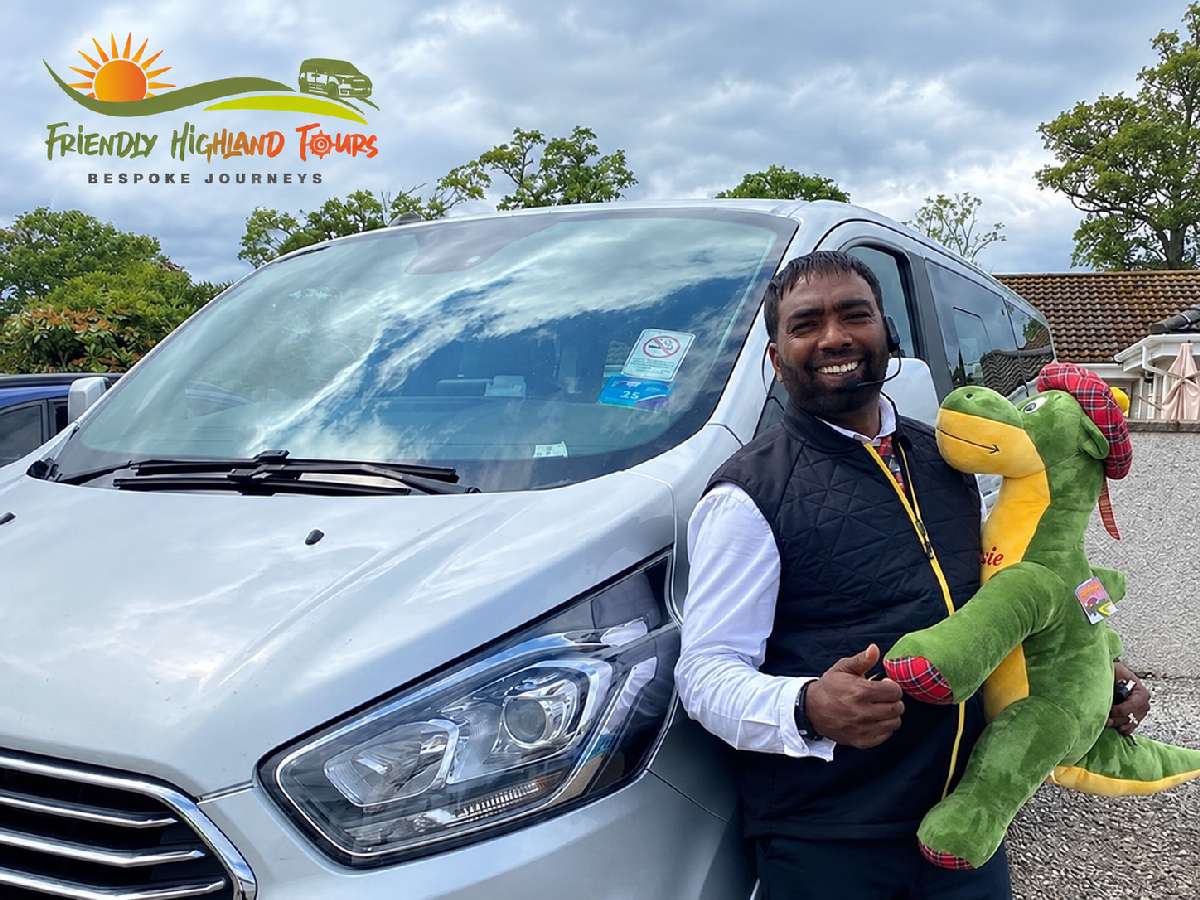 Aleman holding a toy dinosaur beside his tour vehicle